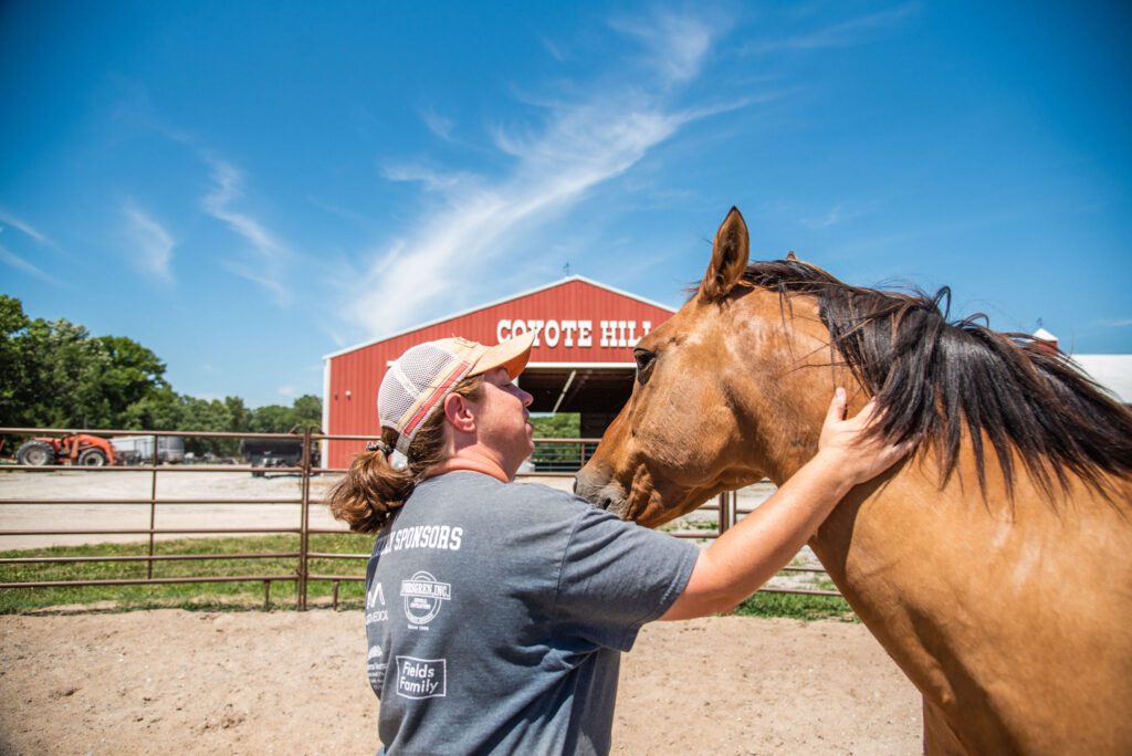 A Coyote Hill Foster Care Ministries Wrangler comforts a horse. YOP tax credits will benefit the Coyote Hill Equine Program.